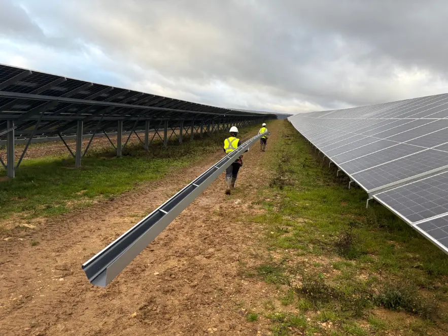 Équipe Alu G transportant une gouttière aluminium en continu sur la ferme solaire de Chazan à Chamboeuf pour l’évacuation des eaux pluviales